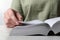 Woman reading holy Bible at grey textured table, closeup