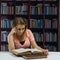 Woman reading an open old book in front of a book shelf