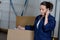 Woman receiving call while preparing warehouse package