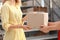 Woman receiving parcel from deliveryman on blurred background, closeup.