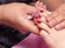 Woman receiving toenail pedicure service by pedicurist at nail salon. Beautician coating red gel color toenail at nail salon