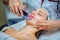 Woman receiving ultrasonic facial exfoliation at cosmetology salon.