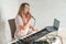 A woman records a vocal lesson using a laptop and accompanying on a keyboard while at home. The teacher sings a song