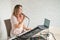 A woman records a vocal lesson using a laptop and accompanying on a keyboard while at home. The teacher sings a song