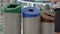 Woman recycles paper into the trash can with paper, plastic and glass sign. Waste sorting and recycling