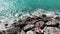 Woman in red beautiful dress with hands apart in air standing on rocky cliff beach with sea waves colliding with rocks splashing w