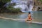 Woman in red bikini look water at Erawan Waterfall and natural