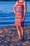 A woman in a red and blue knitted dress with a Missoni zigzag pattern on the beach in summer