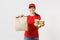 Woman in red cap, t-shirt giving fast food order isolated on white background. Female courier holding paper packet with