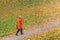 Woman in red coat walking on path in autumn meadow