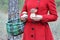 A woman in a red coat with a wicker basket is holding two beautiful boletus edulis edible mushrooms, ceps, penny buns gathered in