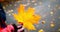 Woman in a red coat with a yellow leaf. A beautiful woman\\\'s hand in a black transparent glove