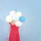 Woman in red dotty dress holding pastel balloons