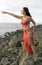 Woman in red dress on coastal stones