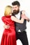 Woman in red dress and man in vest cuddling while dancing. Bearded hipster and attractive lady at dancing contest