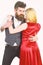 Woman in red dress and man in vest cuddling while dancing. Bearded hipster and attractive lady at dancing contest