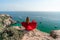 Woman in a red dress on the sea. Rear view of a happy woman in a red long dress posing on a rock high above the sea sees