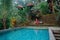 Woman in the red dress sitting on the tropical balcony near the pool