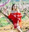 Woman in red dress standing near blooming peach tree