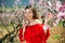 Woman in red dress standing near blooming peach tree