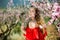 Woman in red dress standing near blooming peach tree