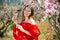 Woman in red dress standing near blooming peach tree