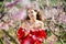 Woman in red dress standing near blooming peach tree
