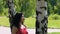 Woman in red dress standing under birch tree in park waiting for date partner