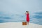 Woman in red dress with suitcase looking in binoculars