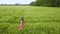 A woman in red dress walking in green wheat field.