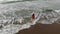 Woman in red dress walking into the water by sand beach on the seaside on sunset, inspirational freedom happy holidays