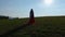 Woman in a Red Dress and a White Scarf Standing Before the Sun on a Meadow