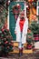 Woman  in red funny in decorated illuminated twinkle lights glowing xmas tree near house