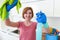 Woman with red hair in rubber washing gloves holding cleaning spray bottle and kitchen cloth smiling rubbing proud