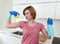 Woman with red hair in rubber washing gloves holding cleaning spray bottle and scourer