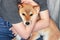 A woman with red hair tightly hugs a cute red dog Shiba Inu, sitting on her lap at home. Close-up. Trust, calmness, care