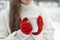 Woman in red knitted mittens holds cup of hot drink outdoors. Close-up of girls hands. Warm drinks in winter