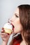 Woman with red lips eating a cake with cream and a cherry on the light background. Delicious cupcake in a womans hand close-up
