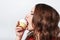 Woman with red lips eating a cake with cream and a cherry on the light background. Delicious cupcake in a womans hand. Lips in a