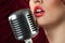 Woman with red lips singing in microphone