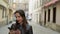 Woman with red lips uses smartphone and strolls along the medieval street