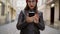 Woman with red lips uses smartphone and strolls along the medieval street