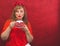 Woman in red posing on the red background. spotted cup with saucer in the hands