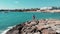 Woman in red on rocky beach cliff. Lady in red dress enjoying sun and warm wind at coral bay cyprus. Successful female in red and