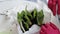 Woman in red rubber gloves straightens paper on flower pots around planted flowers