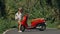 Woman on red scooter in white clothes drive on forest road trail. Dancing trip. One girl caucasian tourist in sunglasses