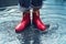 Woman with red short boots standing in a puddle of rain water
