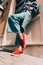 Woman in a red stylish suede loafer shoes, blue jeanse, white shirt and trendy checkered coat posing on the street. Pair