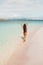 Woman in red swimsuit walking by amazing paradise tropical beach. Summer concept