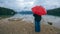 Woman with red umbrella contemplates on rain